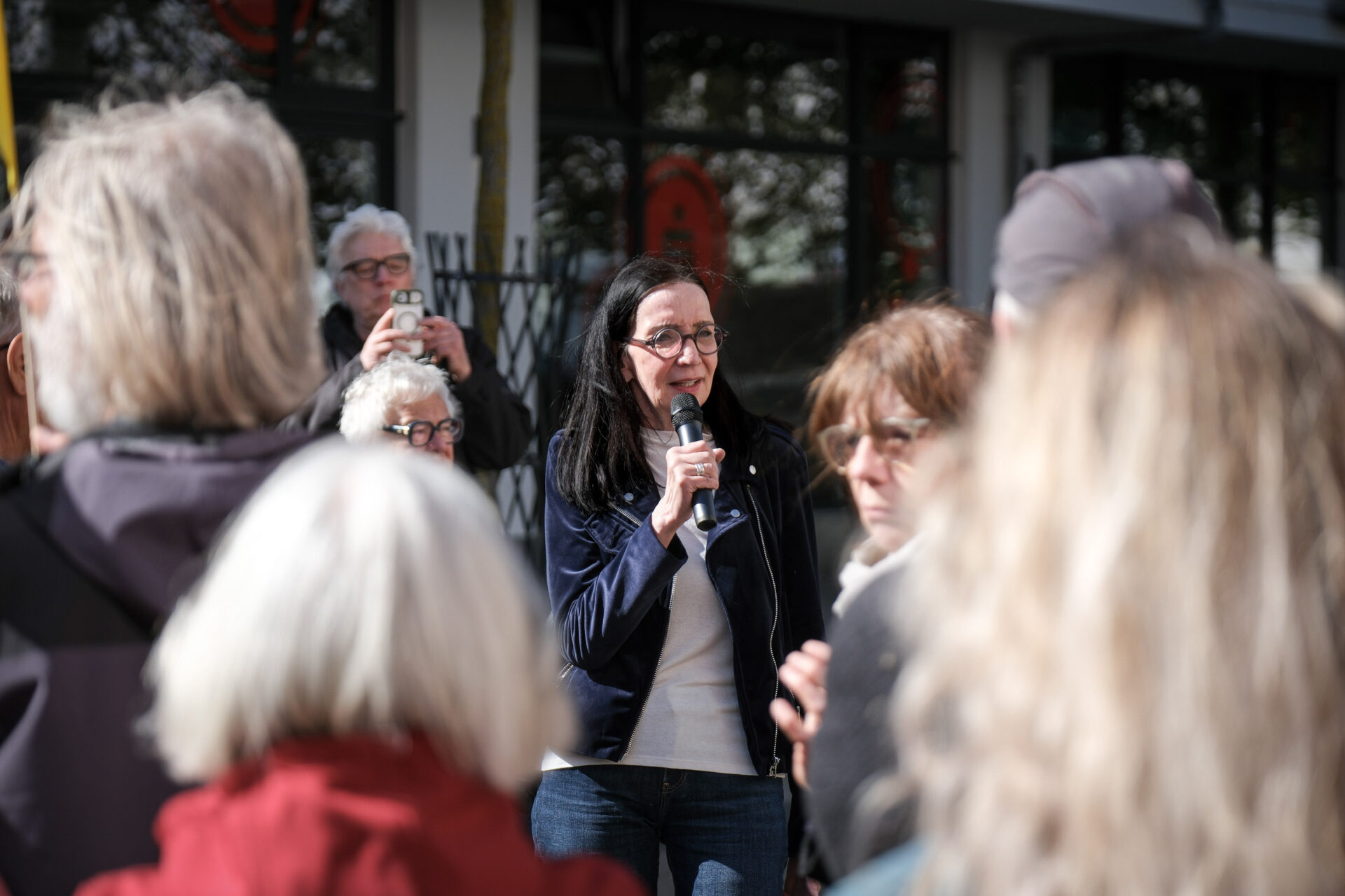 Eine Person hält ein Mikrofon und spricht vor Publikum.