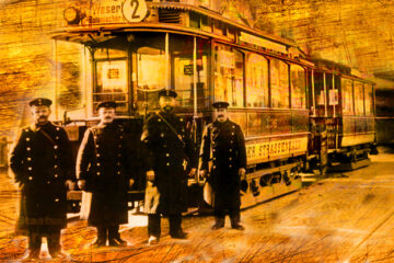 Ein Historisches Bild. Drei Männer stehen vor einer alten Straßenbahn.