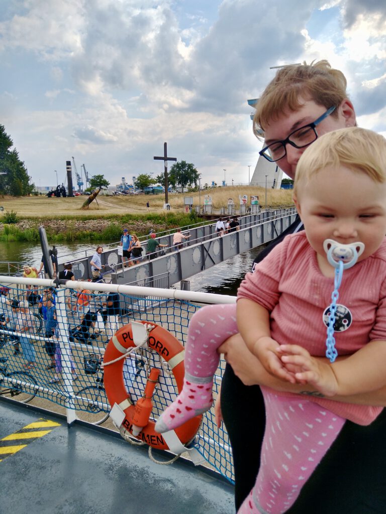 Eine Frau hält ihr Kleinkind auf dem Arm. Beide sind auf der Weserfähre Bremen.