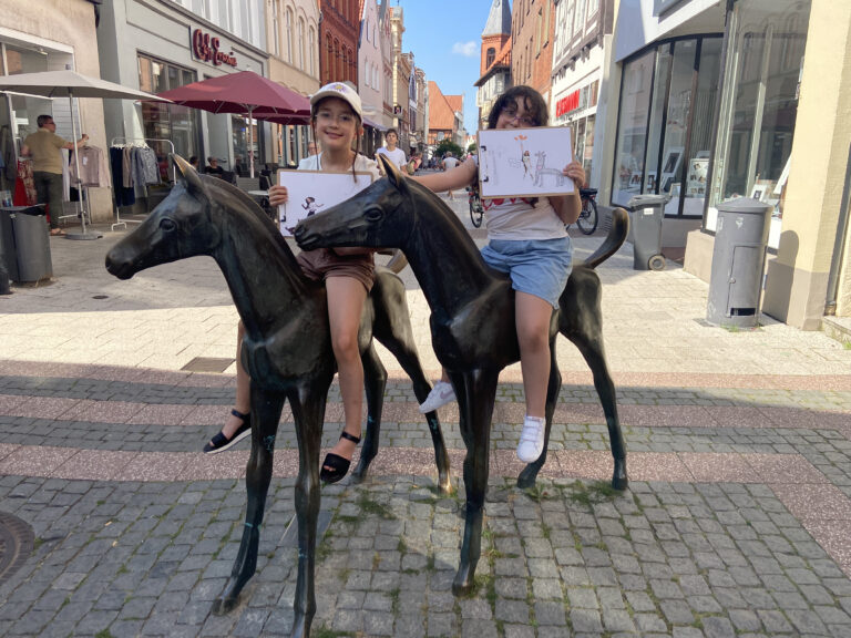 In der Fußgängerzone der Stadt Verden stehen zwei Bronzestatuen. Es sind zwei Fohlen. Zwei Mädchen posieren auf den Fohlen sitzend und zwigen ihre Skizzenbilder