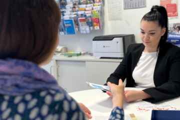 An einem runden Tisch sitzen sich zwei Personen gegenüber im Beratungsgespräch.