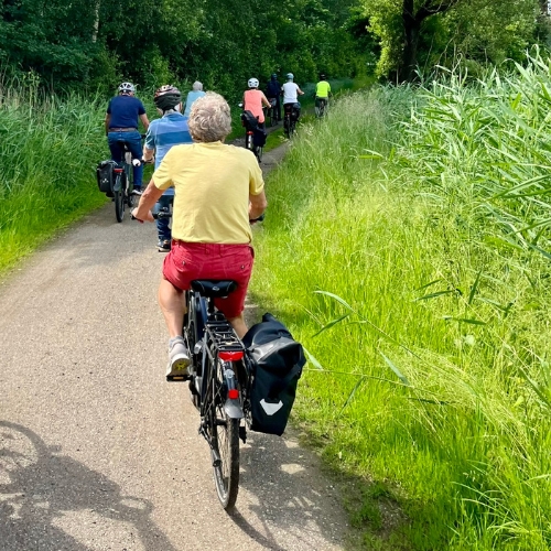 Auf einem Wanderweg sind Radfahrer von hinten zu sehen, die einen Ausflug machen.