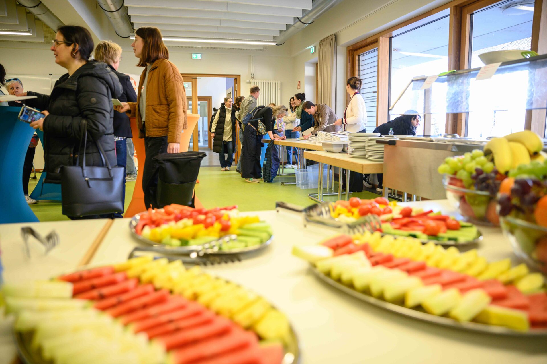 Ein Blick über einen Tisch, auf dem sich Obst und Gemüsehäppchen befinden: Gezeigt wird die Ankommensitzation bei einer Fachtagung, bei der die Teilnehmenden zur Anmeldung kommen.