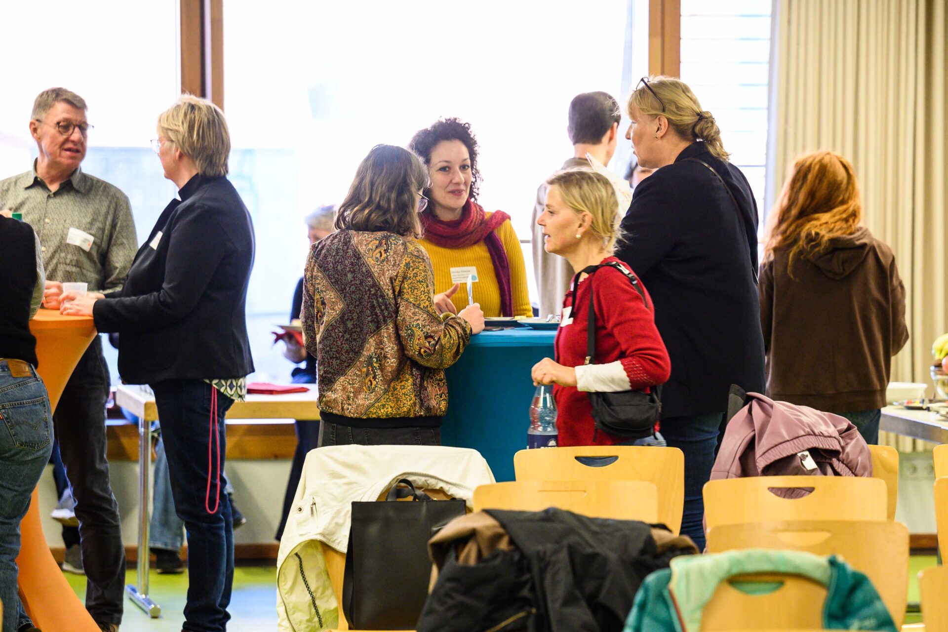 Menschen unterhalten sich stehend angeregt in kleinen Gruppen rund um Stehtische