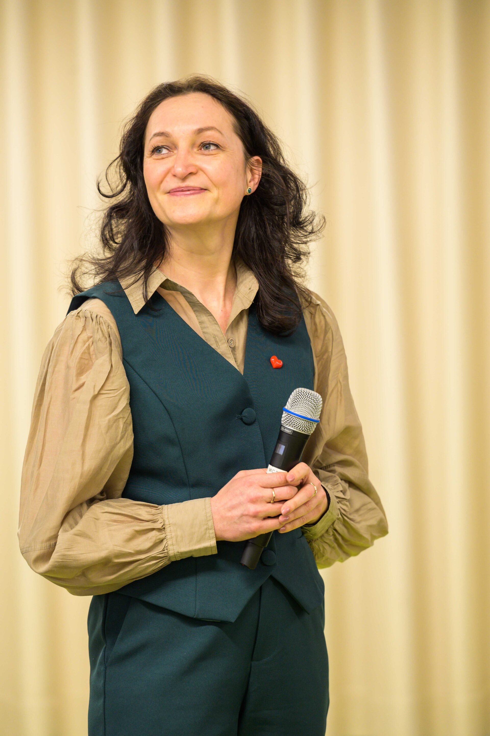 Das ist ein Protraitfoto von Dr. Irina Volf, die ein Mikrofon in der Hand hält.