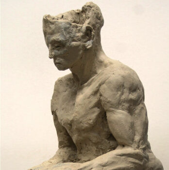 Eine Skulptur aus Ton von einer sitzenden Person in Seitenansicht.