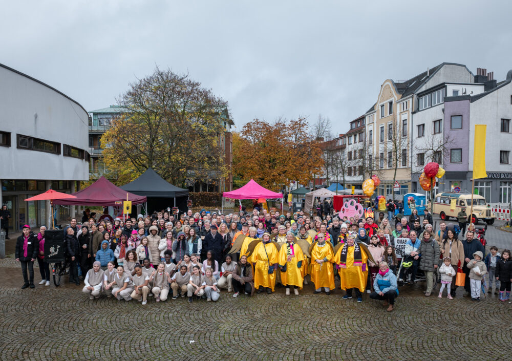 Auf dem Gröpelinger Bibliotheksplatz haben sich alle Beteiligten des Festival Feuerspuren versammelt zu einem Gruppenfoto. Manche sind kostümiert.