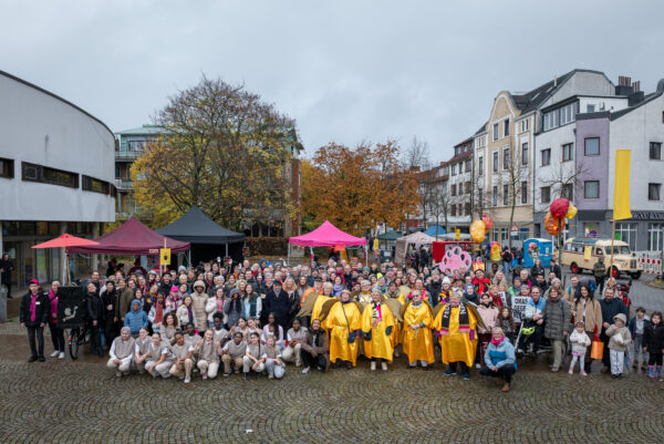 Auf dem Gröpelinger Bibliotheksplatz haben sich alle Beteiligten des Festival Feuerspuren versammelt zu einem Gruppenfoto. Manche sind kostümiert.