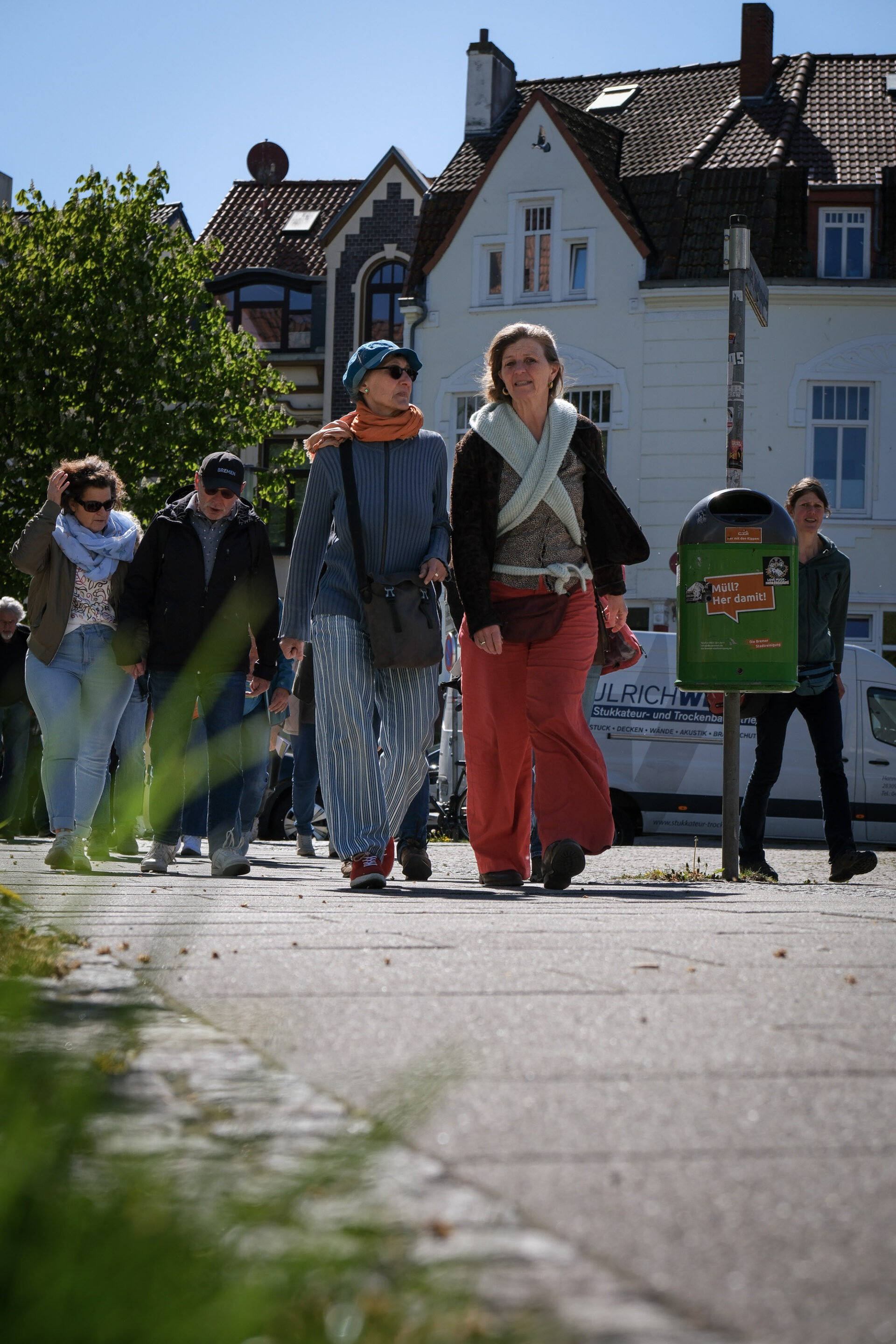 Mehrere Personen spazieren ins Gespräch vertieft die Straße entlang.
