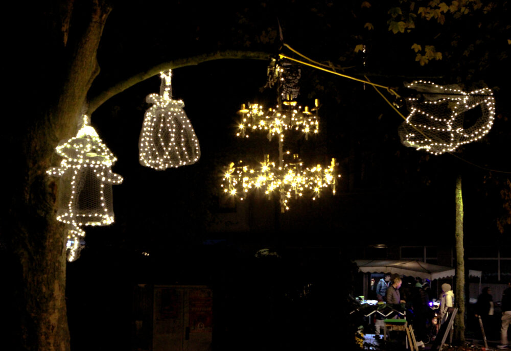 Lichtobjekte leuchten zart in Bäumen in der Dunkelheit.