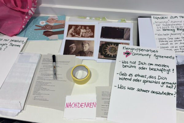 Auf einem Tisch sind schriftstücke und Fotos zu sehen.