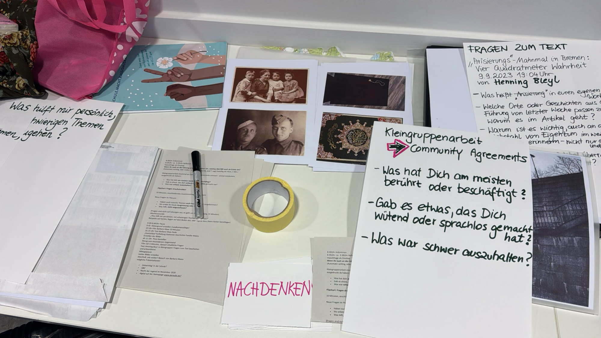 Auf einem Tisch sind schriftstücke und Fotos zu sehen.