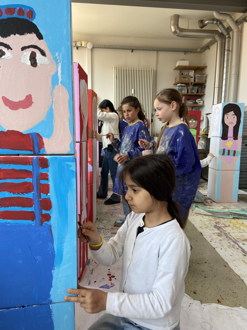 Kinder malen das eigene Portrait auf einen Karton.