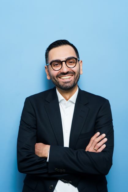 Das ist ein Proträtfoto von Professor Doktor karim Fereidooni, der mit verschränkten Armen in die Kamera lächelt.