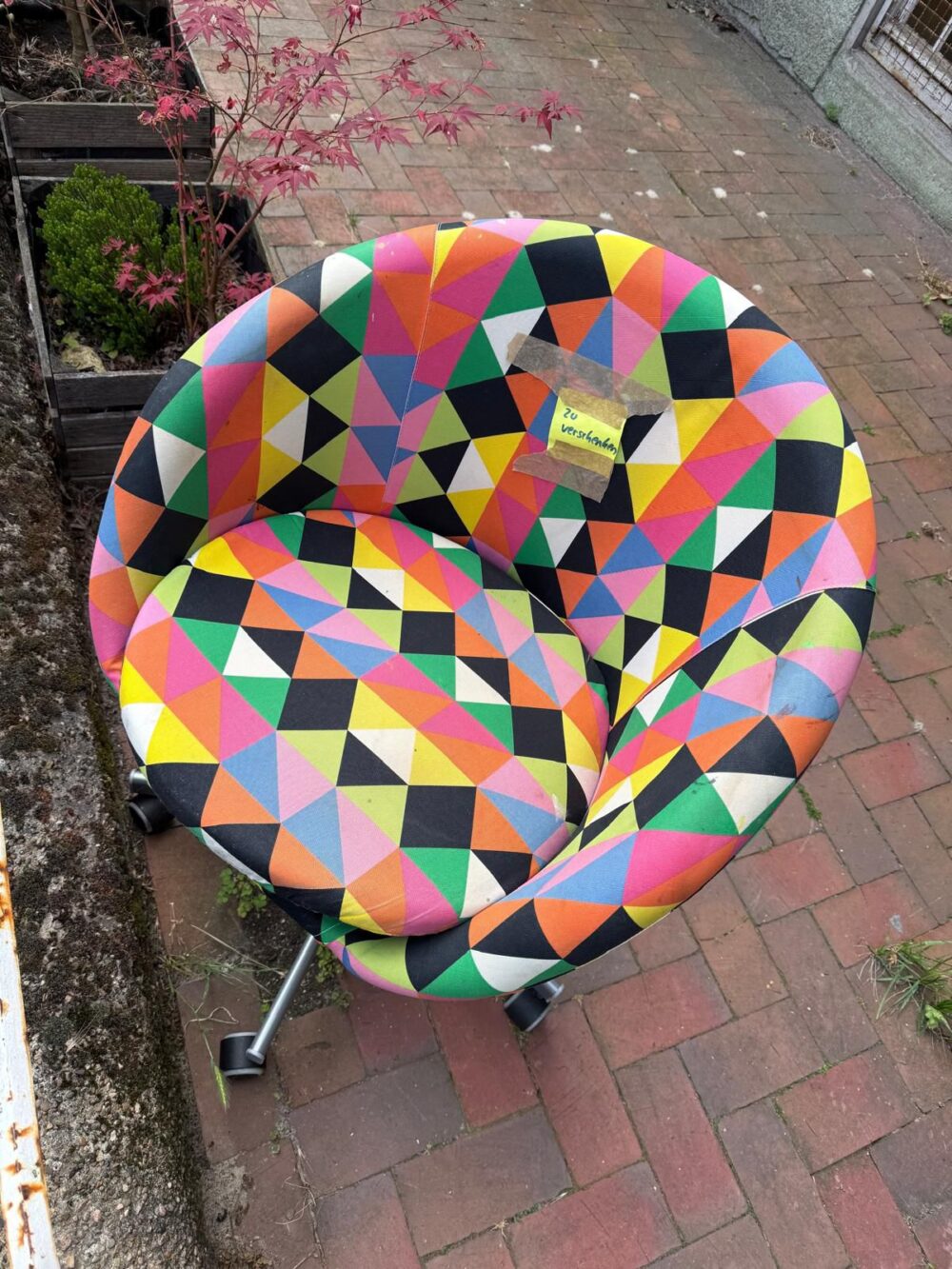Ein kunterbunter Sessel. Darauf ist ist ein gelbes Post It angebracht. Dort steht: Zu Verschenken