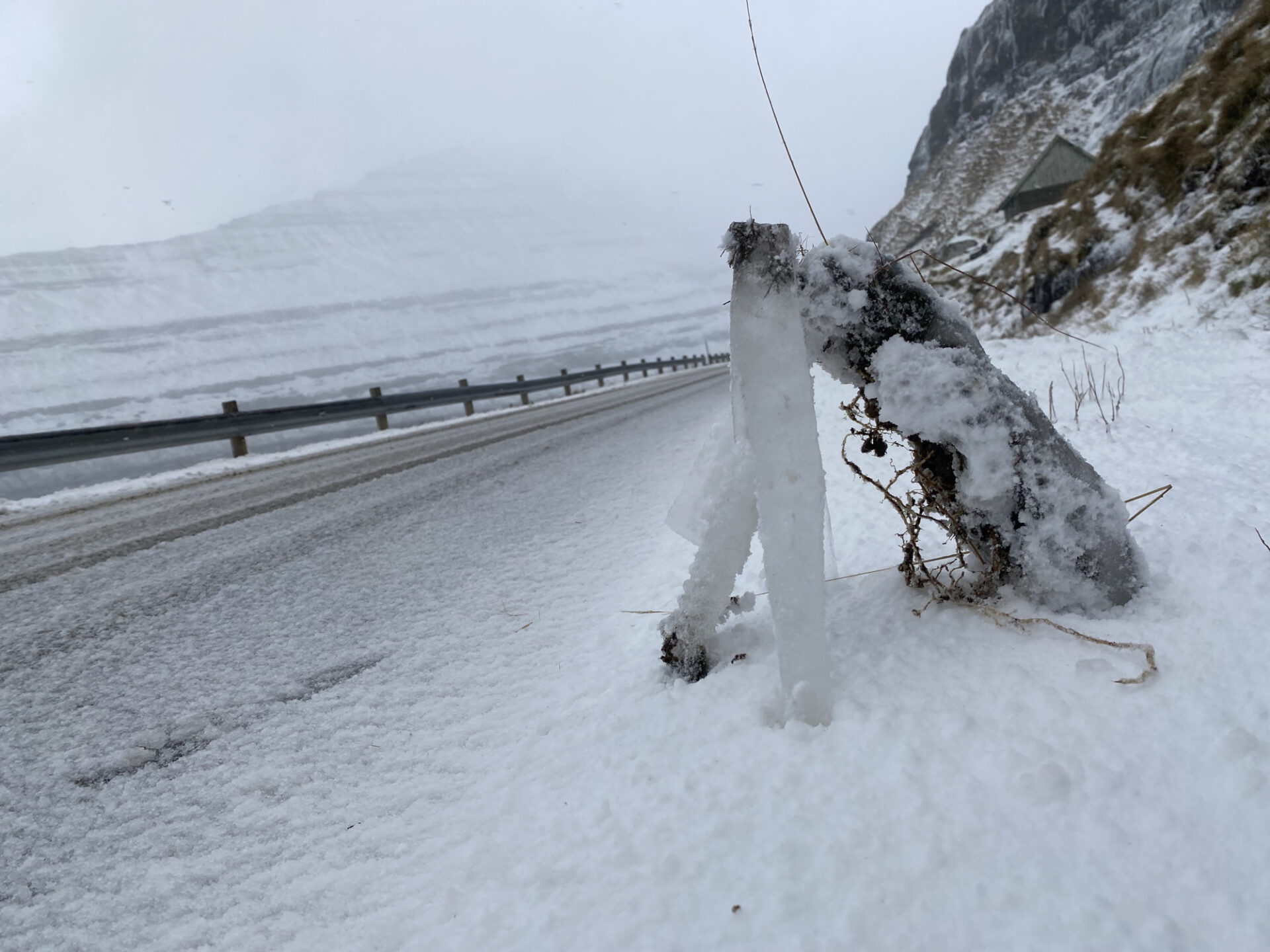 In einer winterlich verschneiten Landschaft an einer Straße sind vereiste Stücke zu einer Skulptur zusammengestellt.