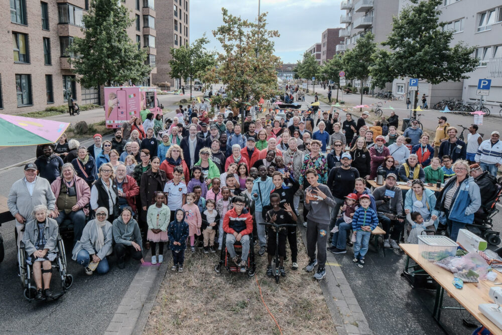 Das Gruppenfoto zeigt circa 100 Menschen, die sich versammelt haben un dalle in die Kamera schauen.