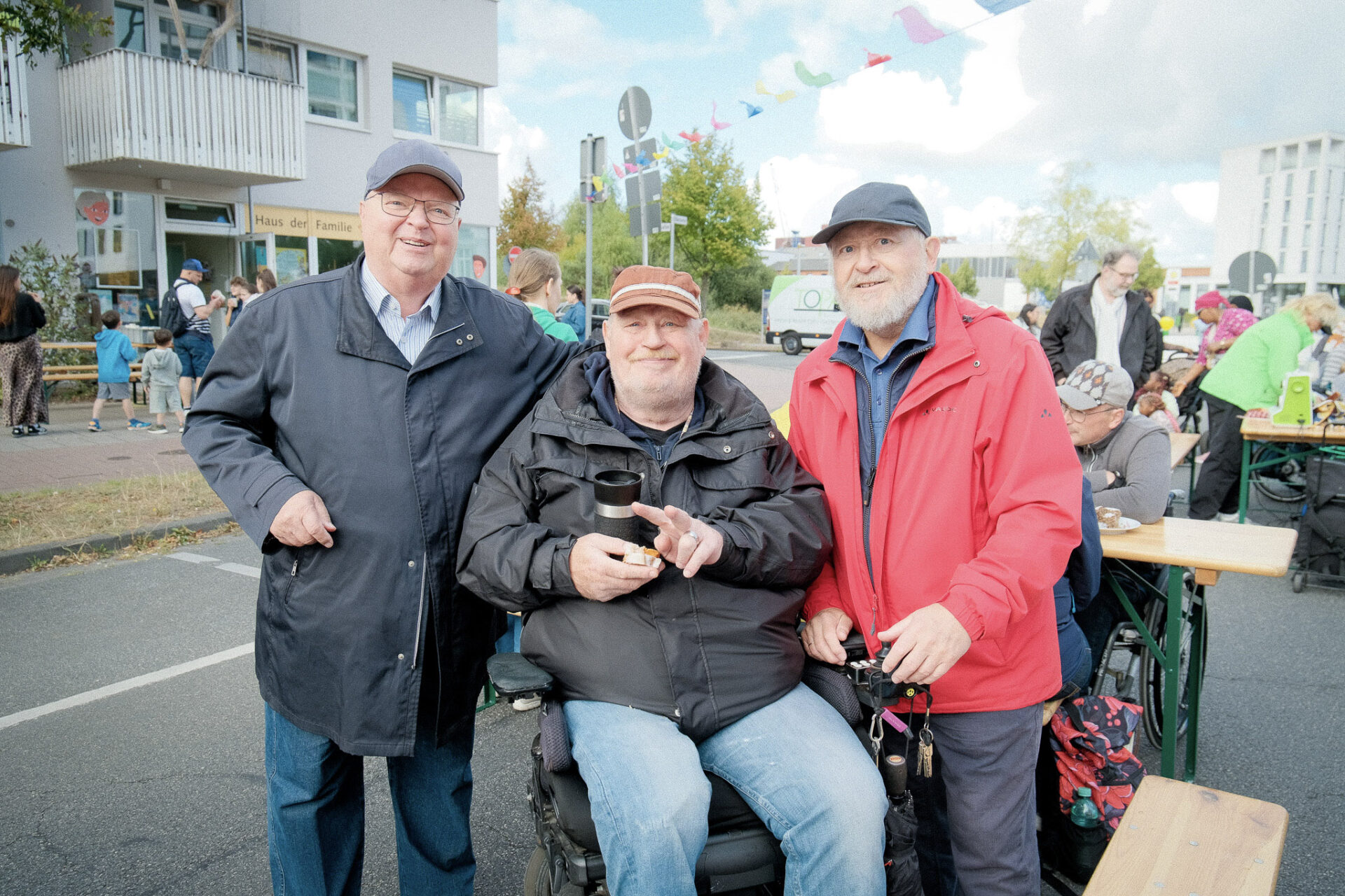 Eine Gruppe von drei Männern, alle tragen eine Kappe, schauen in die Kamera und lachen.