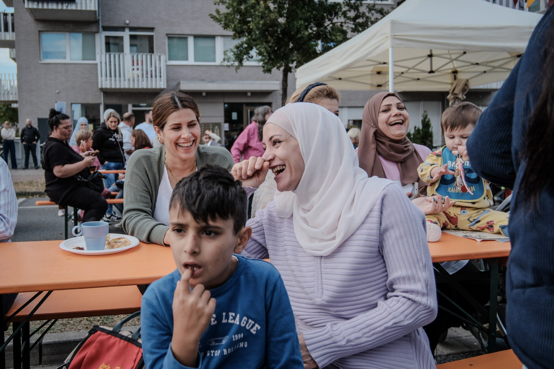 Eine Gruppe von Frauen und ein Kind sitzen an einem Picknick Tisch. Fast alle lachen.