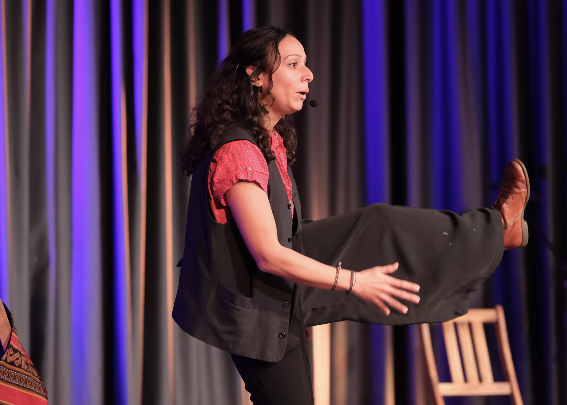 Auf einer Bühne steht eine Person in der Bewegung erstarrt auf einem Bein.