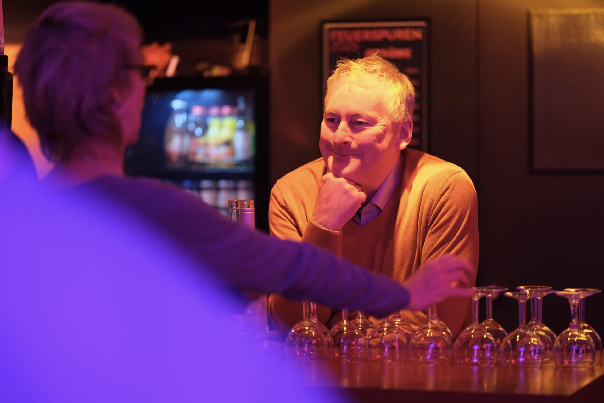 Ünber einen Tresen lächelt eine Person einer anderen zu.