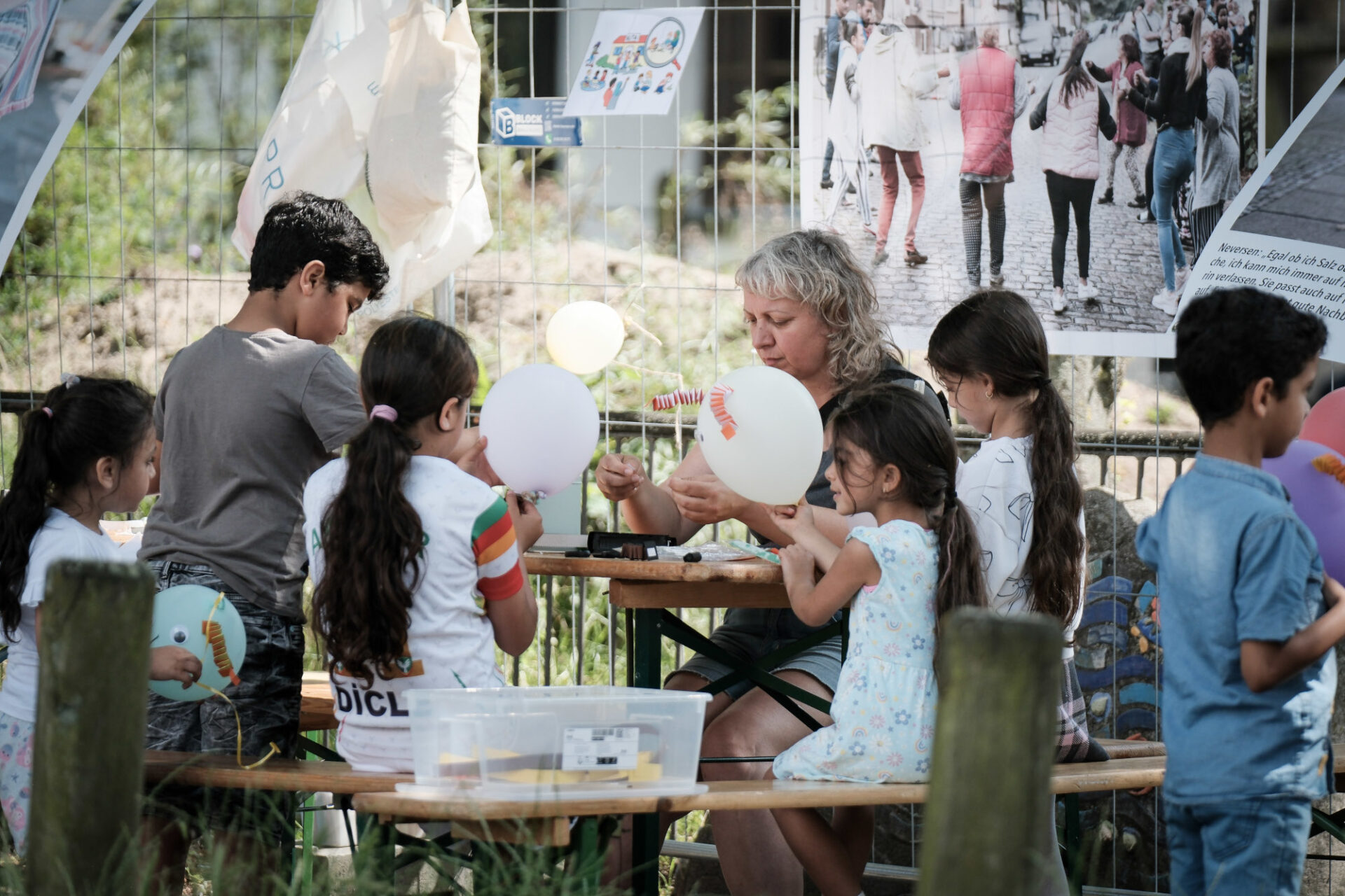 Kinder und eine Eerwachsene Personen arbeiten kreativ und konzentriet im Freien an einem Biertisch