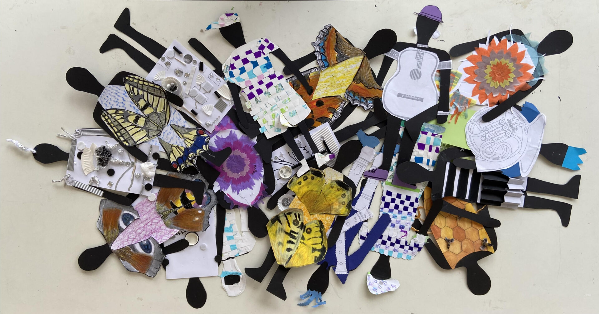 Lauter kleine Figuren mit unterschiedlichen Kleidungsstücken aus Papier liegen auf einem Haufen übereinander.