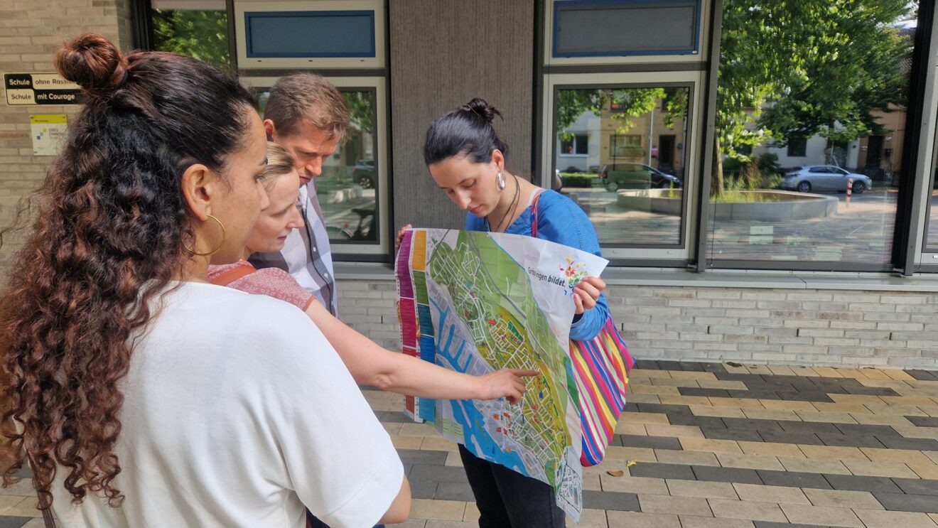 Teilnehmer:innen einer Führung schauen sich einen Stadtplan an