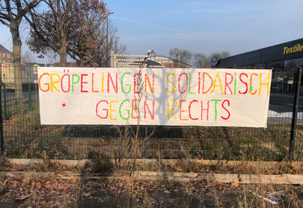 An einem Zaun hängt ein Transparent auf dem in bunten Buchstaben steht: "Gröpelingen solidarisch gegen Rechts"
