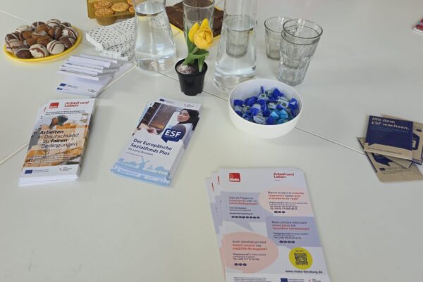Auf einem weißen Tisch liegen Info-Flyer und Knabbereien
