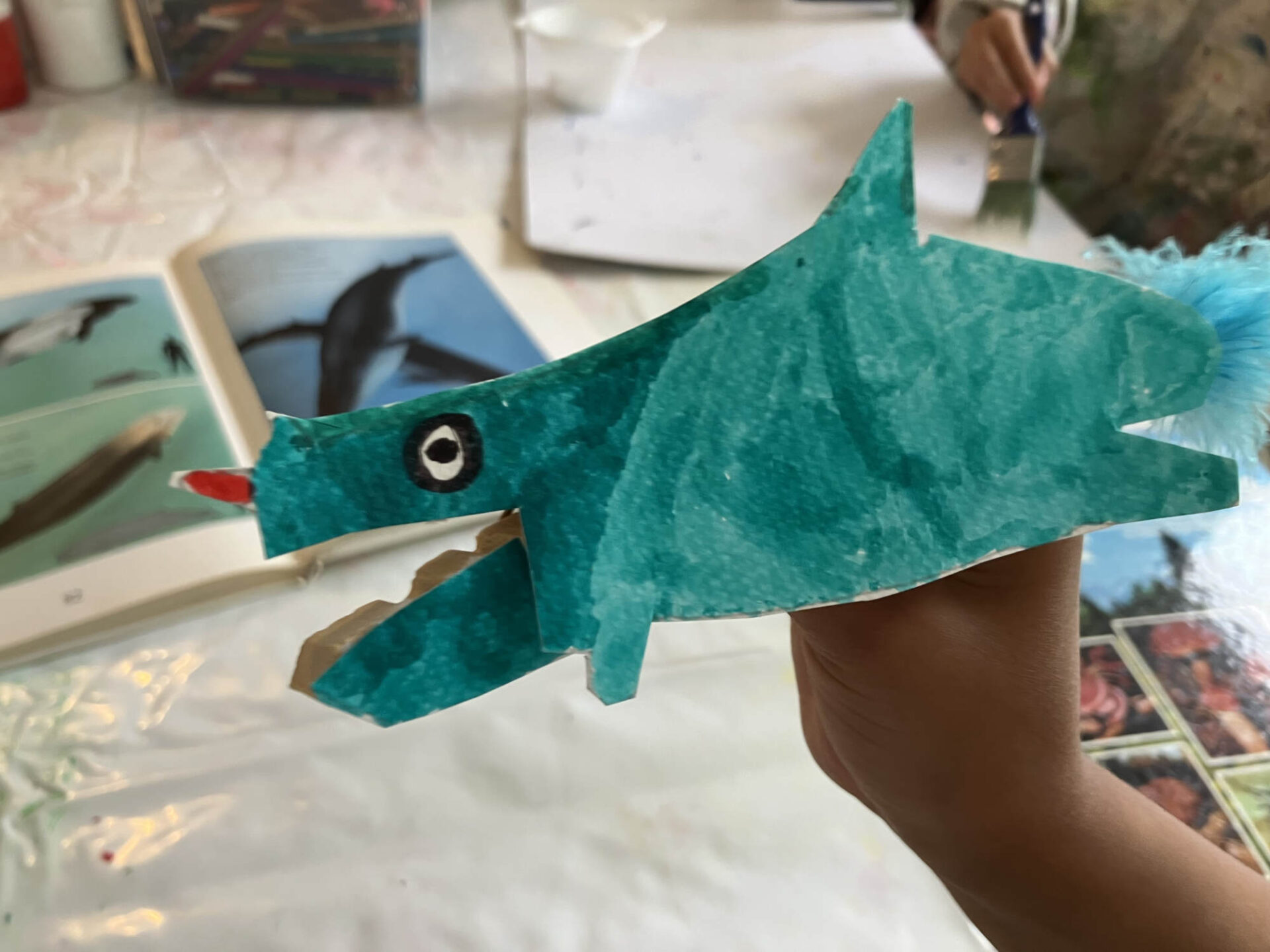 Ein Dinosaurier aus Papier wird von einer Kinderhand hochgehalten