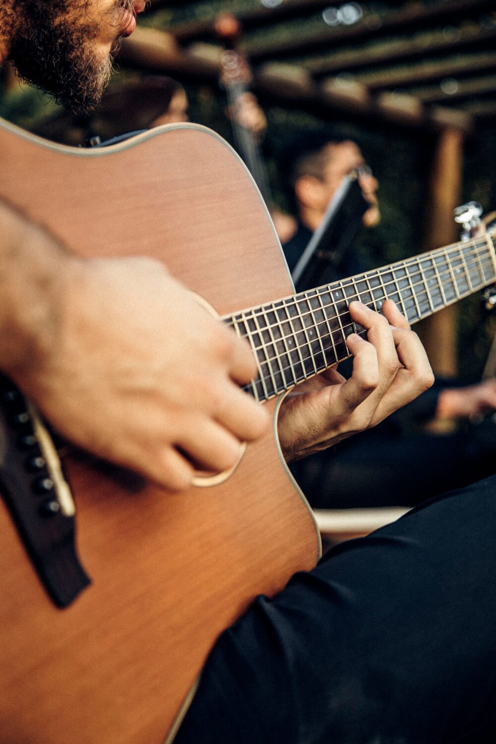 Eine akustische Gitarre in Großaufnahme wird von einer Person gehalten, die nur mit ihren Händen zu sehen ist.