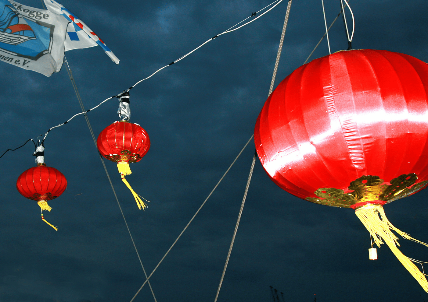 Rote Lampionons zieren einen Abendhimmel. Im Bild links oben ist eine Fahne von Hal Över zun dvon der Hansekogge Bremen e.V. zu sehen.