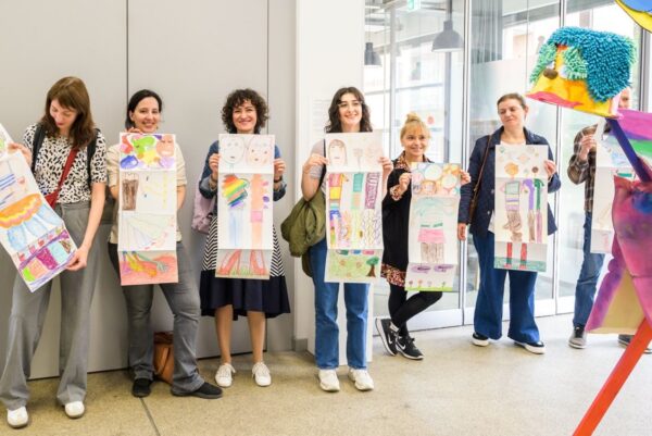 Sieben Personen halten Plakate in der Hand mit Zeichnungen darauf.