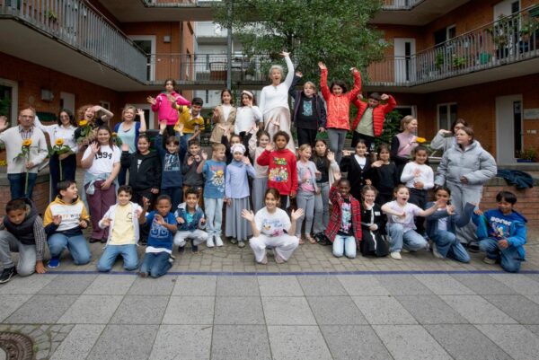 Dies ist ein Gruppenbild mit vielen Kindern und ein paar erwachsenen Personen.