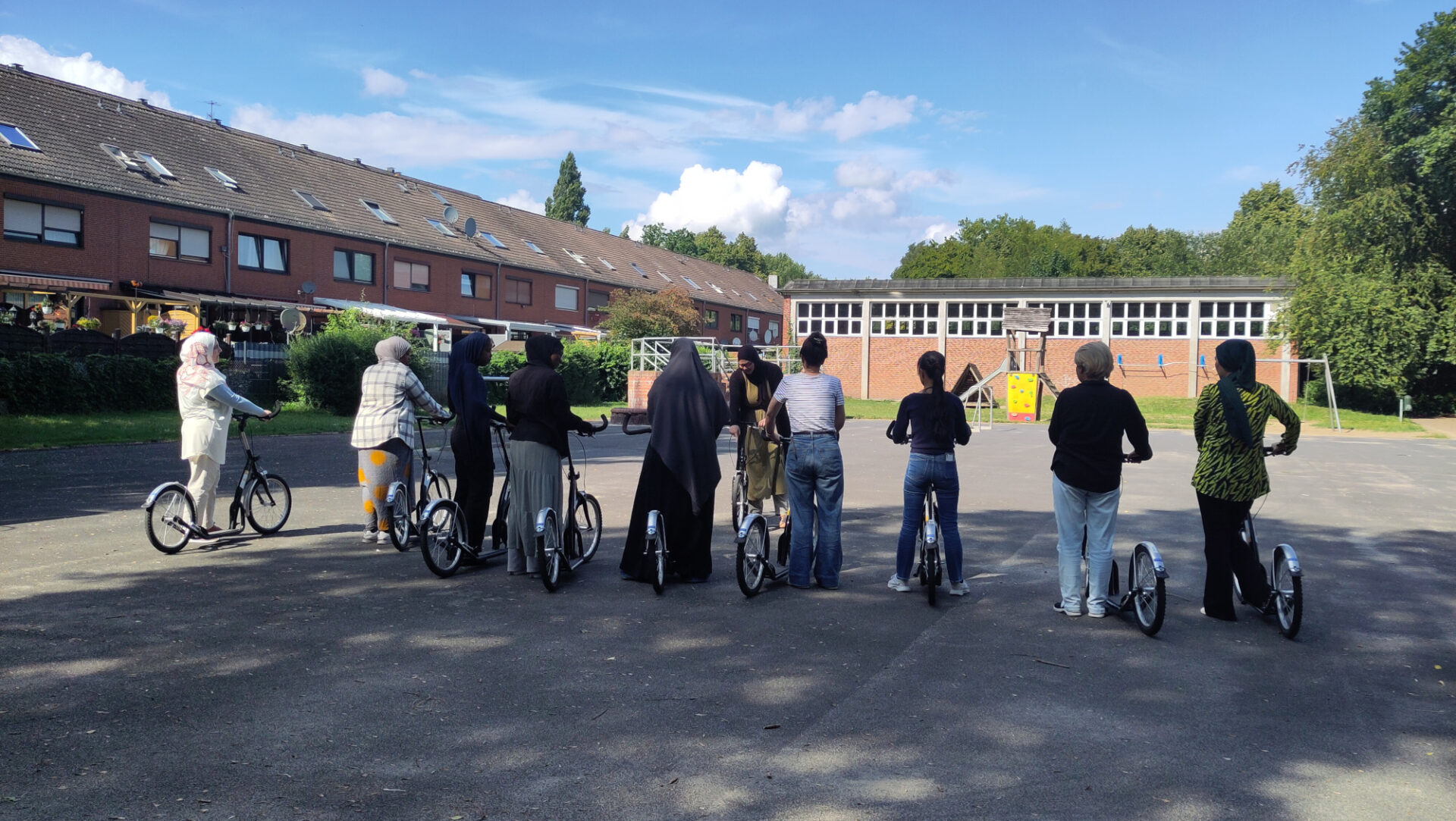 Frauen stehen im Halbkeis auf einem gepflasterten Hof. Jede hält ein Fahrrad fest. Eine weitere Frau erklär ihnen etwas anhand eines Fahrrades.