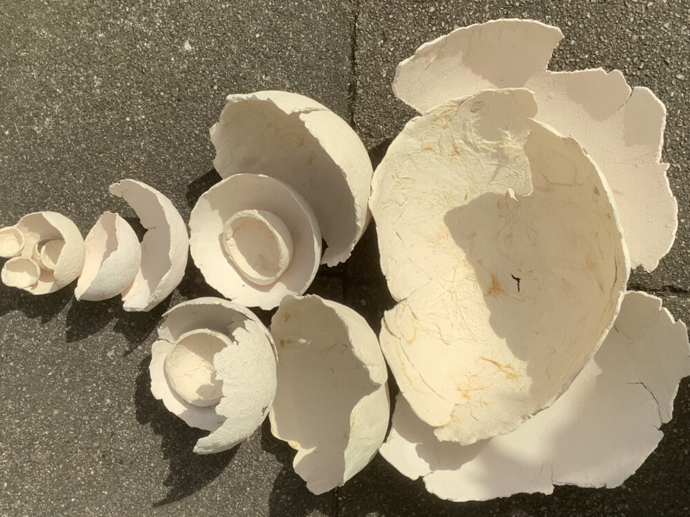 Auf dem Boden liegen verschiedene helle Tonschalen, teilweise ineinandergelegt.