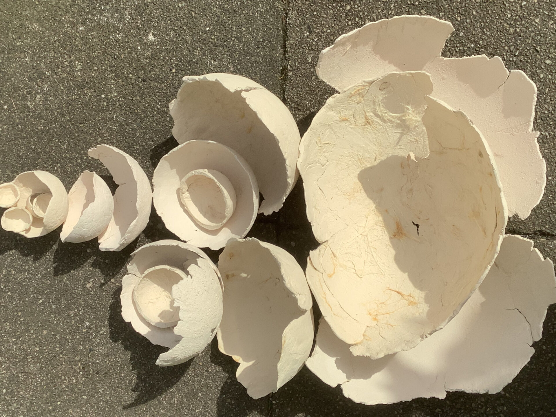 Auf dem Boden liegen verschiedene helle Tonschalen, teilweise ineinandergelegt.