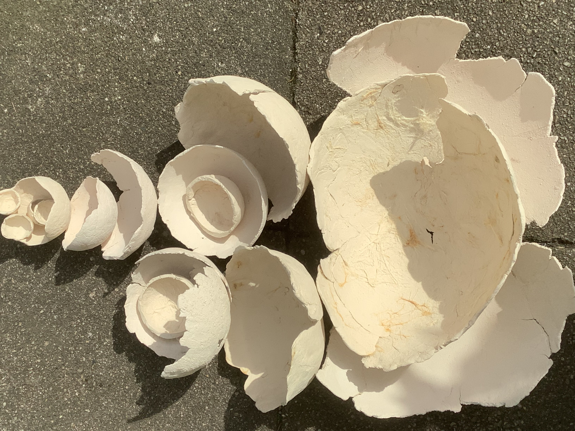 Auf dem Boden liegen verschiedene helle Tonschalen, teilweise ineinandergelegt.