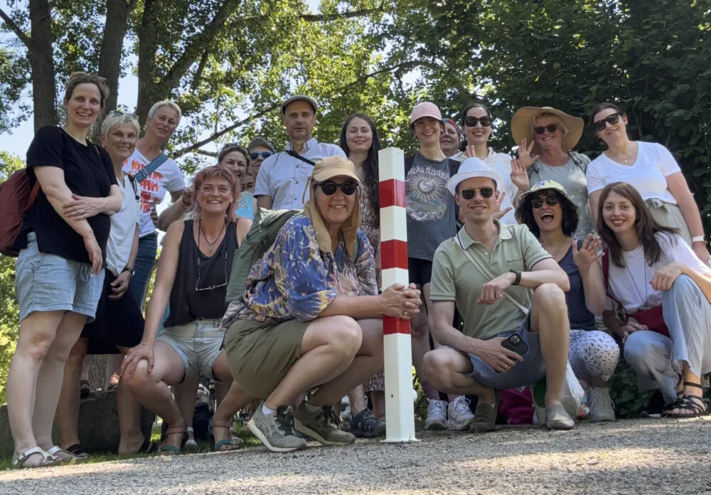 Das ist ein Gruppenfoto vom Team Kultur Vor Ort. Das Foto ist in sommerlicher Stimmung gehalten, im Hintergrund befinden sich Bäume.